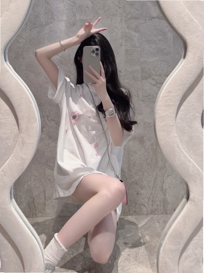 Cô gái xinh đẹp nhìn vào gương, dùng điện thoại che mặt